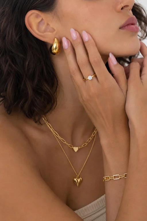 Modelo con aretes de gota, cadenas en capas y pulsera de eslabones Aurea